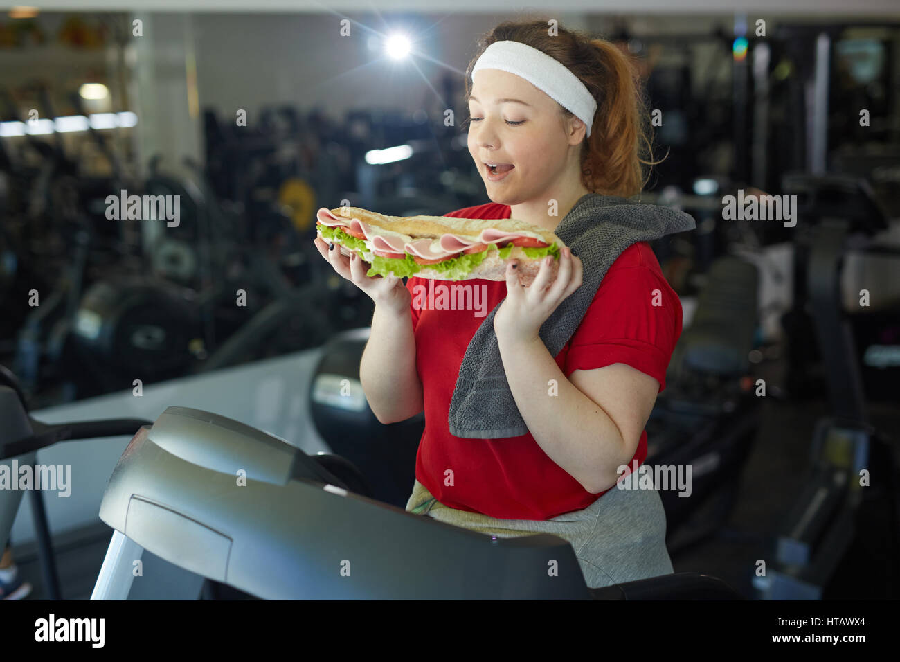 Porträt von niedlichen Fette Frau lecken ihre Lippen, riesige leckere  Sandwich Essen beim Training im Fitness-Studio Stockfotografie - Alamy