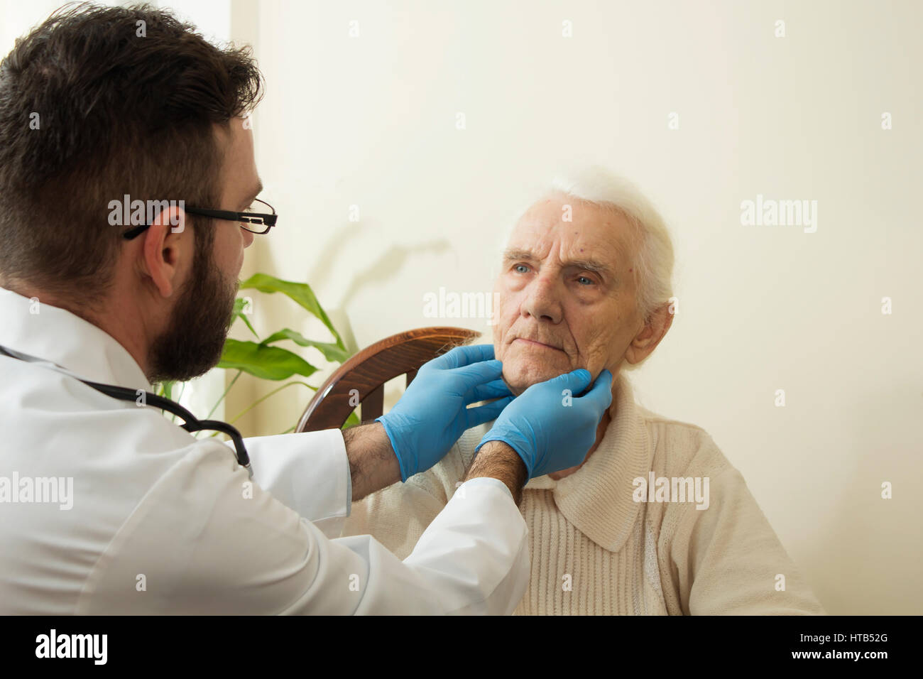 Der Arzt untersucht die Lymphknoten am Hals von einer alten Frau. Stockfoto
