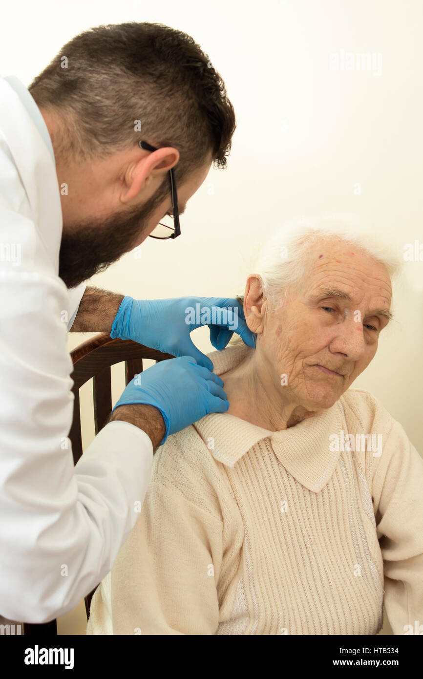 Der Arzt Geriater während des Tests. Arzt untersucht Veränderungen in der Haut einer alten Frau. Stockfoto