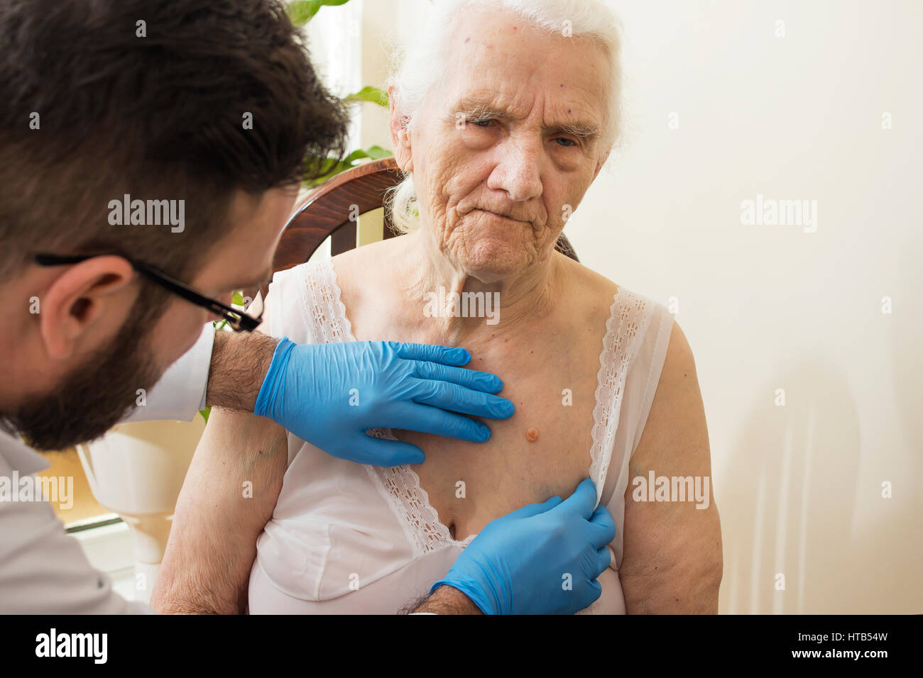 Arzt untersucht Veränderungen in der Haut einer alten Frau. Stockfoto