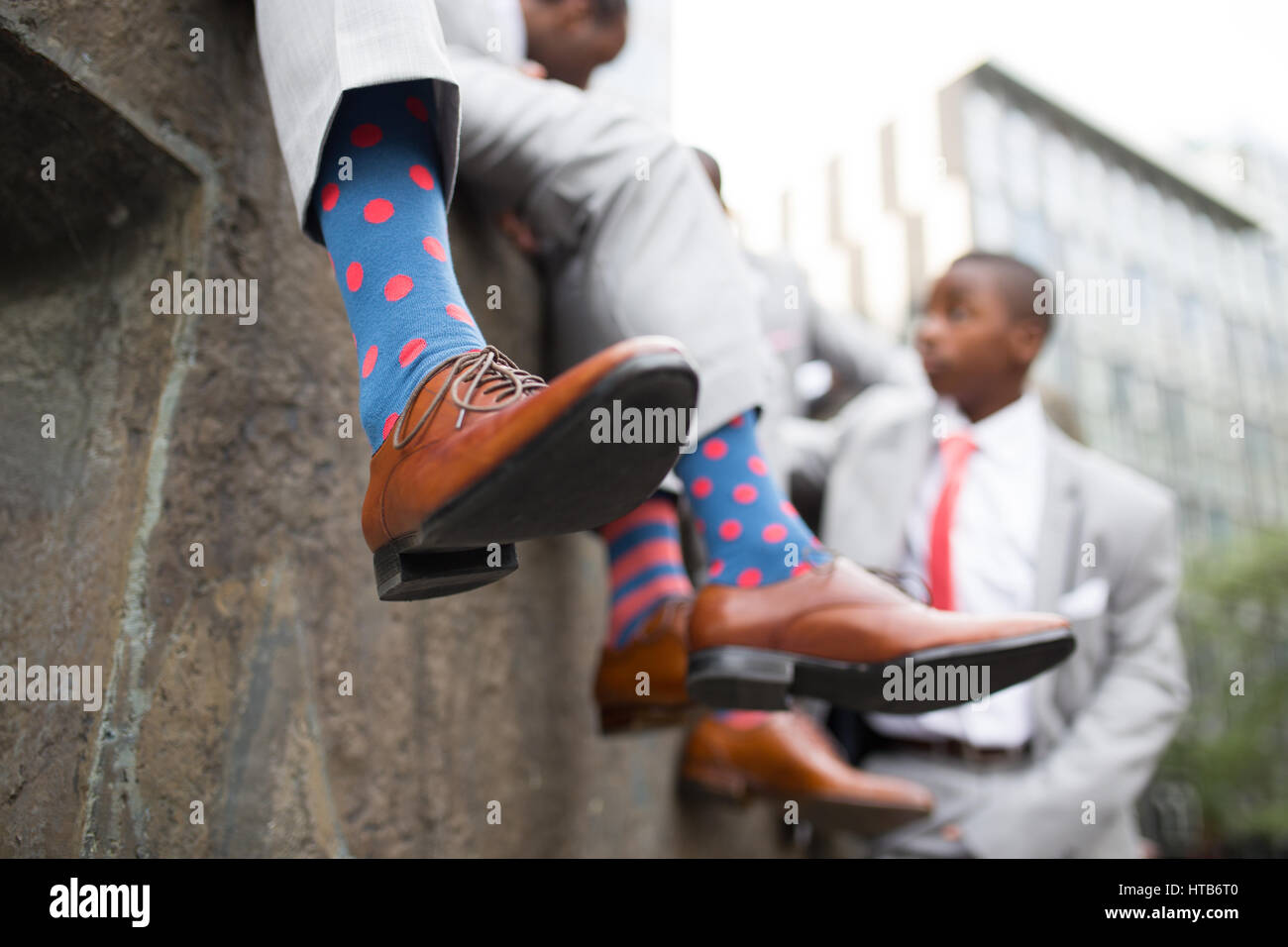 Drei Groomsmen tragen gemusterte Socken, Schuhe und Anzüge mit Krawatten Stockfoto