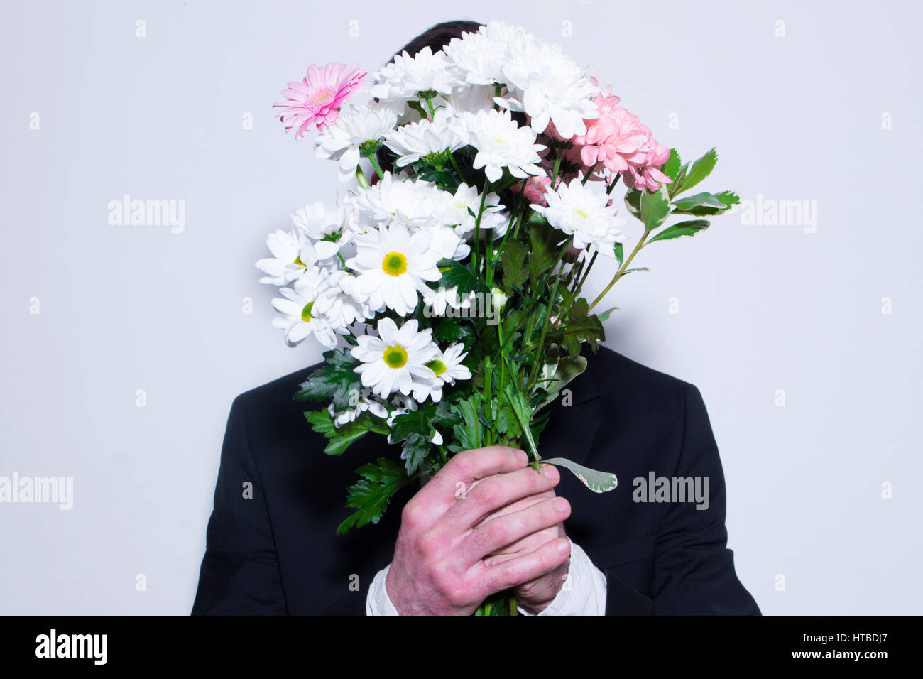 Ein Mann versteckt sein Gesicht mit Blumen Stockfoto