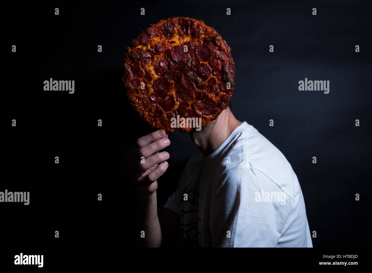 Ein Mann versteckt sein Gesicht mit pizza Stockfoto