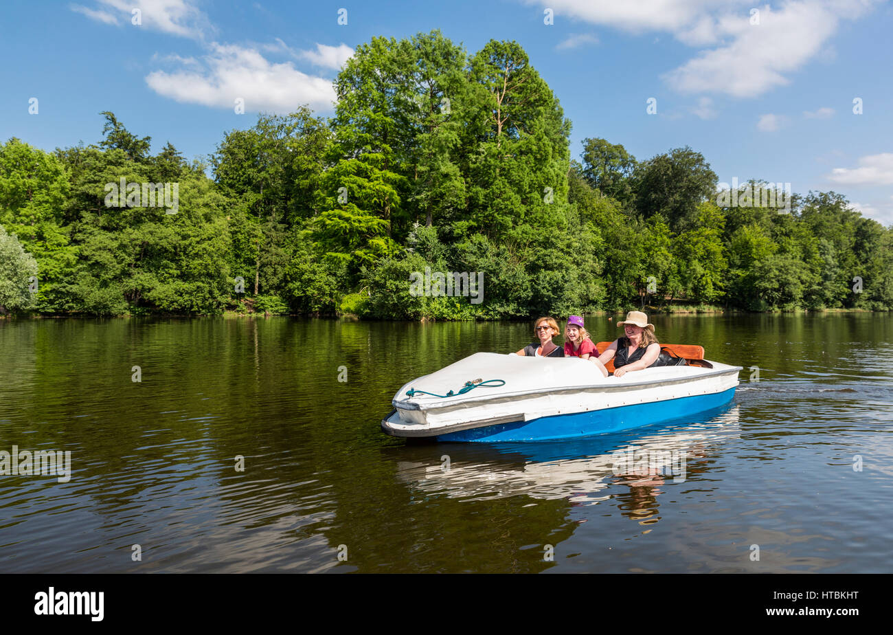 Zwei Frauen und ein Mädchen betreiben ein Paddelboot auf ein ruhiger Fluss, umgeben von dichtem Wald an einem sonnigen Tag; Steinbrucker Teig, Hessen, Deutschland Stockfoto