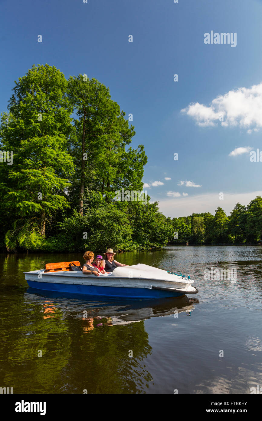 Zwei Frauen und ein Mädchen betreiben ein Paddelboot auf ein ruhiger Fluss, umgeben von dichtem Wald an einem sonnigen Tag; Steinbrucker Teig, Hessen, Deutschland Stockfoto