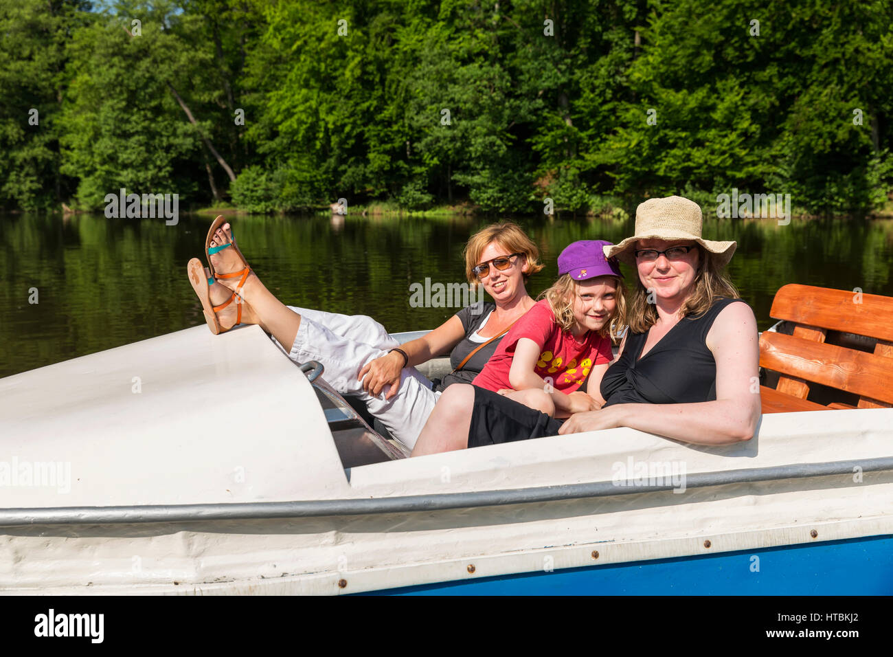 Zwei Frauen und ein Mädchen auf einem Tretboot auf ein ruhiger Fluss, umgeben von dichten Wäldern an einem sonnigen Tag; Steinbrucker Teig, Hessen, Deutschland Stockfoto