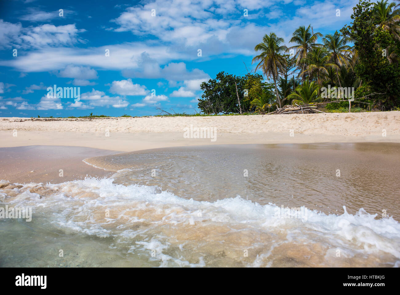 Eine Welle Spritzwasser auf den weißen Sandstrand und dem Dschungel im Hintergrund auf der unbewohnten Insel Cayo Zapatilla in Bocas del Toro; Panama Stockfoto