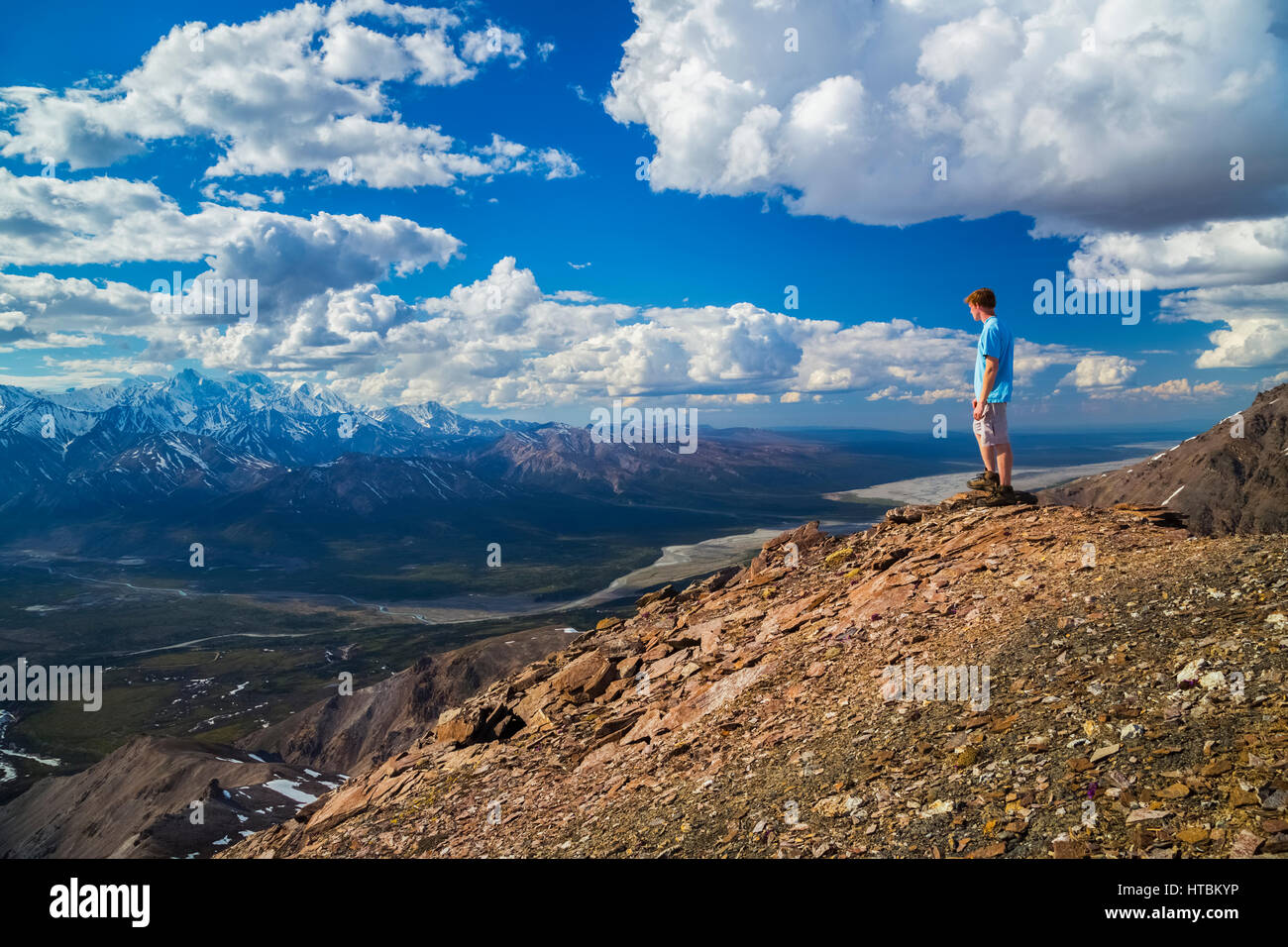 Ein Wanderer steht auf einem Felsvorsprung mit Blick auf das Delta Flusstal in einem Gebiet von der Alaska Range bekannt wie die Delta-Berge Stockfoto