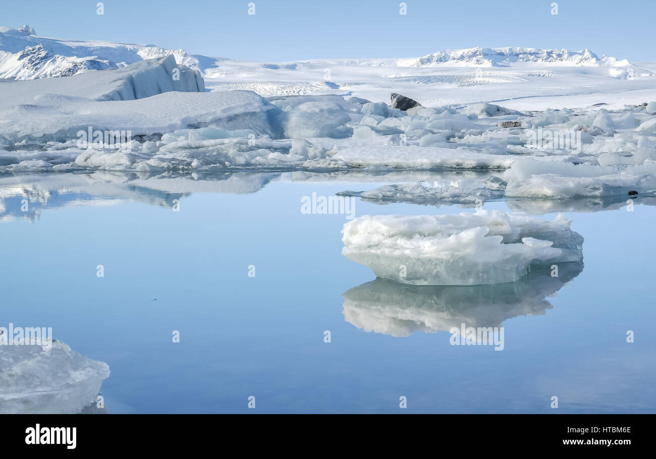 Eisberge an der Jökulsárlón Eisberg Lagune, Island, mit Eis im blauen Gletscherwasser im Winter mit blauem Himmel reflektiert Stockfoto