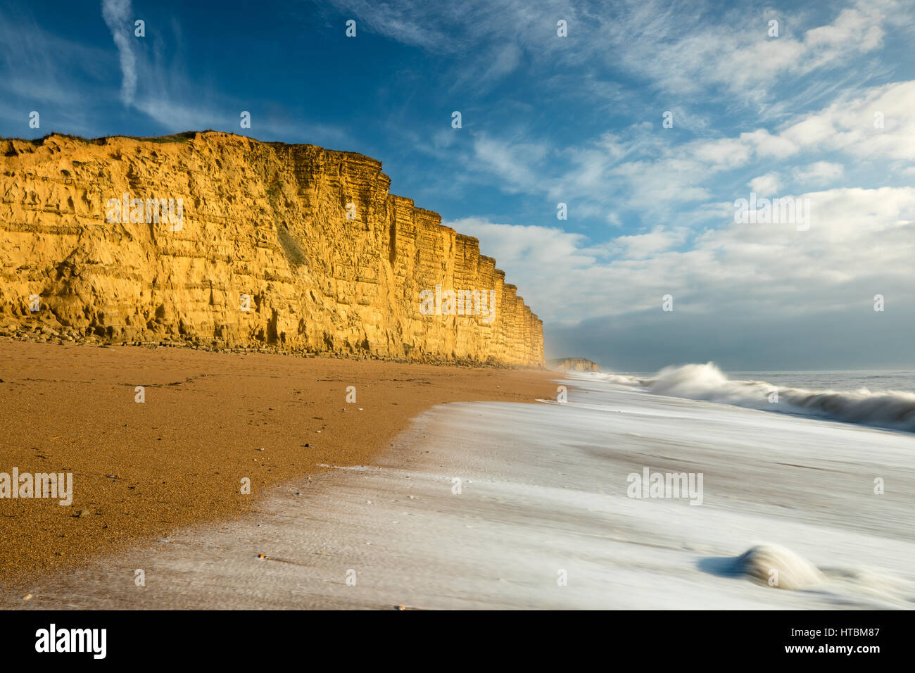 Wellen brechen sich am Strand unter East Cliff, West Bay, Jurassic Coast, Dorset, England, UK Stockfoto