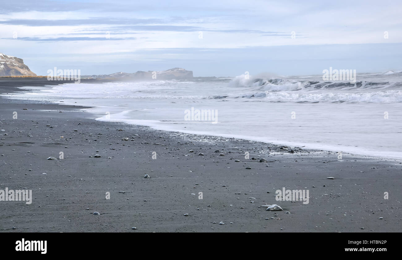 Schwarze Lavastrand mit schaumige Wellen an Vik, Island, im Winter Tag mit stimmungsvollen Abendhimmel und brechende Wellen Stockfoto