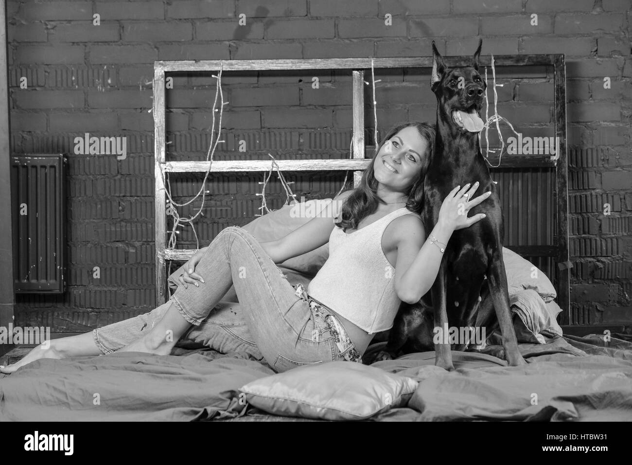 Frau im Bett mit großen schwarzen Dobermann Hund Stockfoto