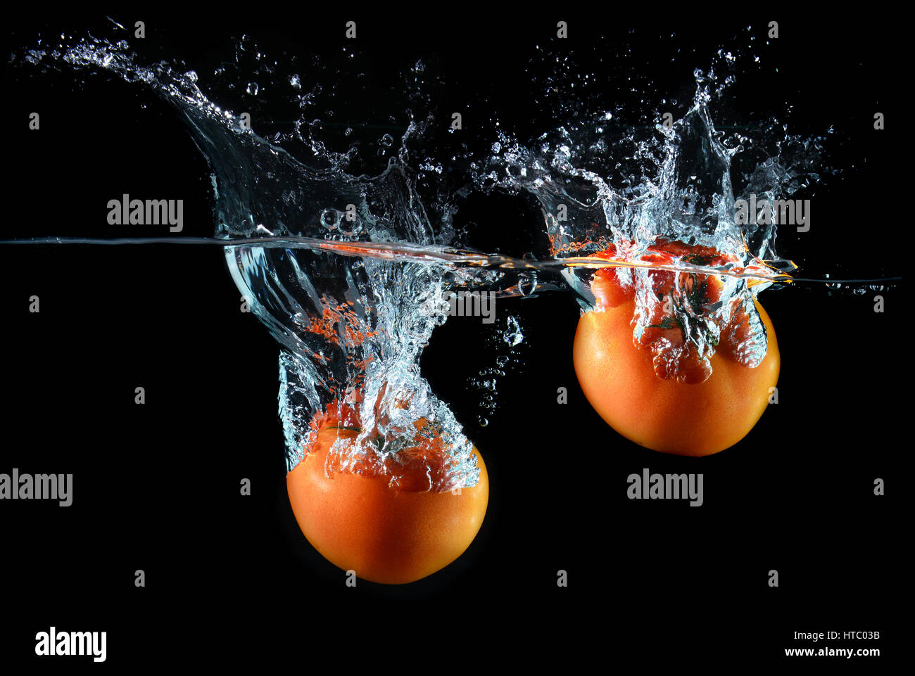 Spritzer Wasser Droping Tomaten und Kunst gemischt im Studio technische Geschwindigkeit und Beleuchtung. Stockfoto