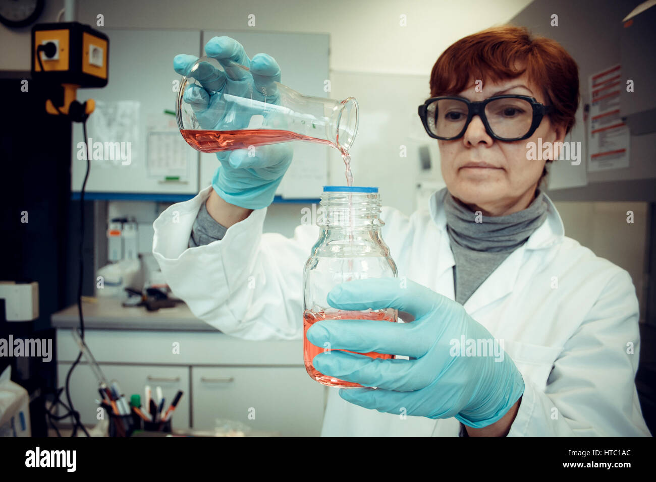 Wissenschaftlicher Mitarbeiter arbeitet mit roter Flüssigkeit im Labor, soft-Fokus Stockfoto Wissenschaftlicher Mitarbeiter arbeitet mit roter Flüssigkeit im Labor, soft-Fokus Stockfoto