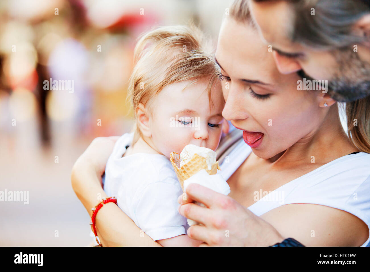 Ein kleinen Jungen ist von seiner Mutter und seinem Vater während mit Eis gefüttert umarmt wird. Stockfoto