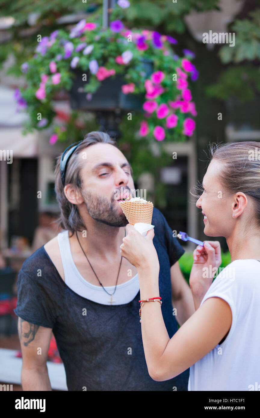 Ein Weibchen füttert ihr Freund oder Ehemann mit Eis auf der Straße. Stockfoto