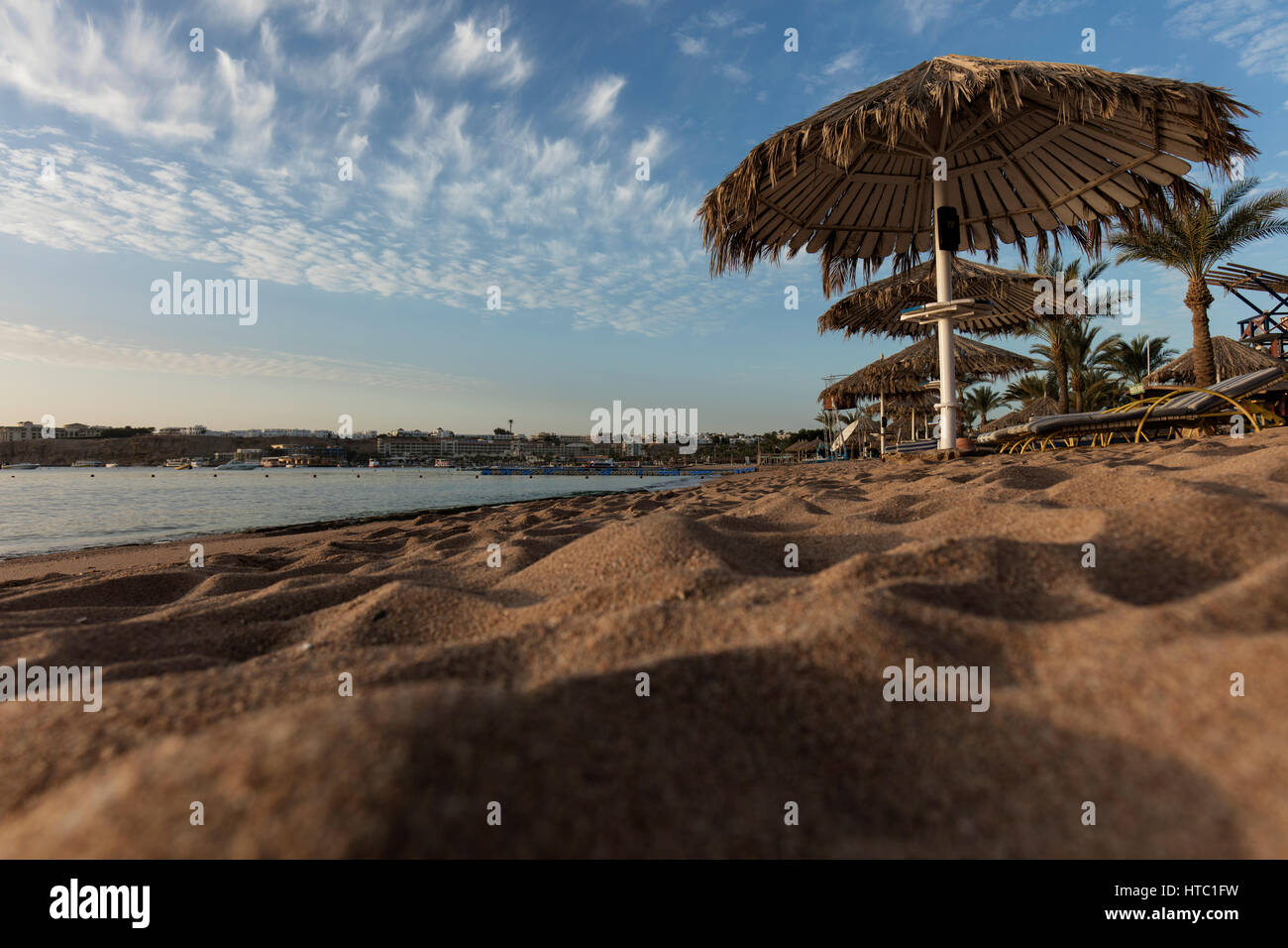 Sandstrand mit strohgedeckten Sonnenschirmen in Ägypten Stockfoto