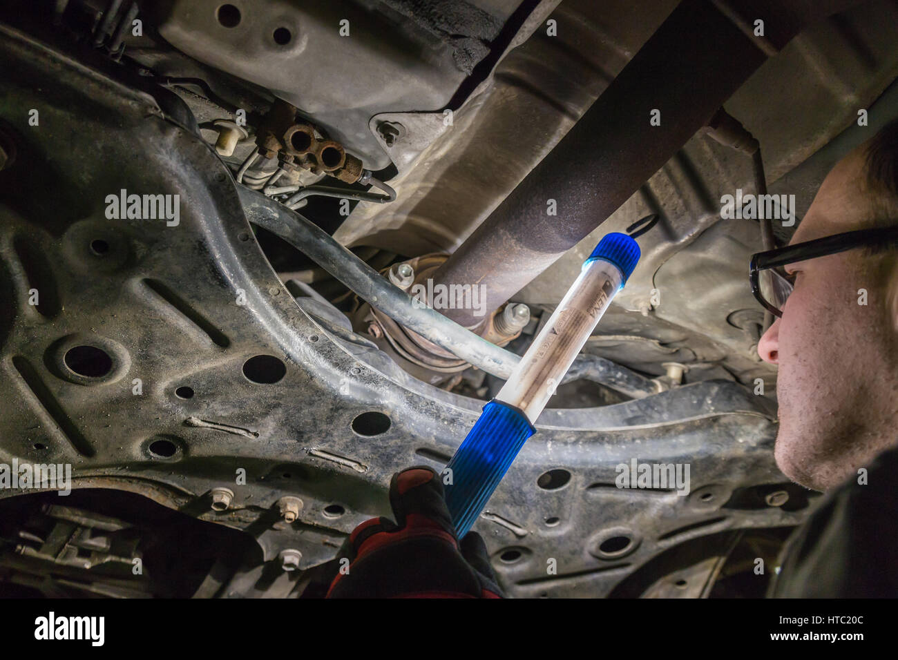 Kfz-Mechaniker betrachten Autoteile auf dem Fahrgestell. Stockfoto