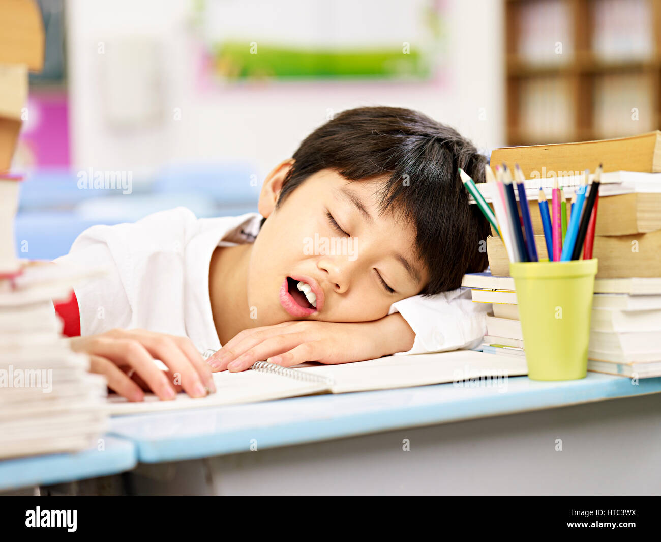 müde und erschöpft asiatischen Grundschule Schüler beim Einschlafen während des Studiums Stockfoto