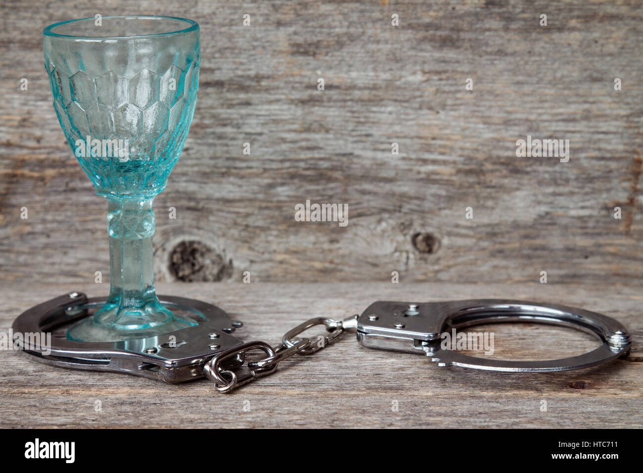 Glas mit Handschellen als Symbol für Alkoholmissbrauch Stockfoto