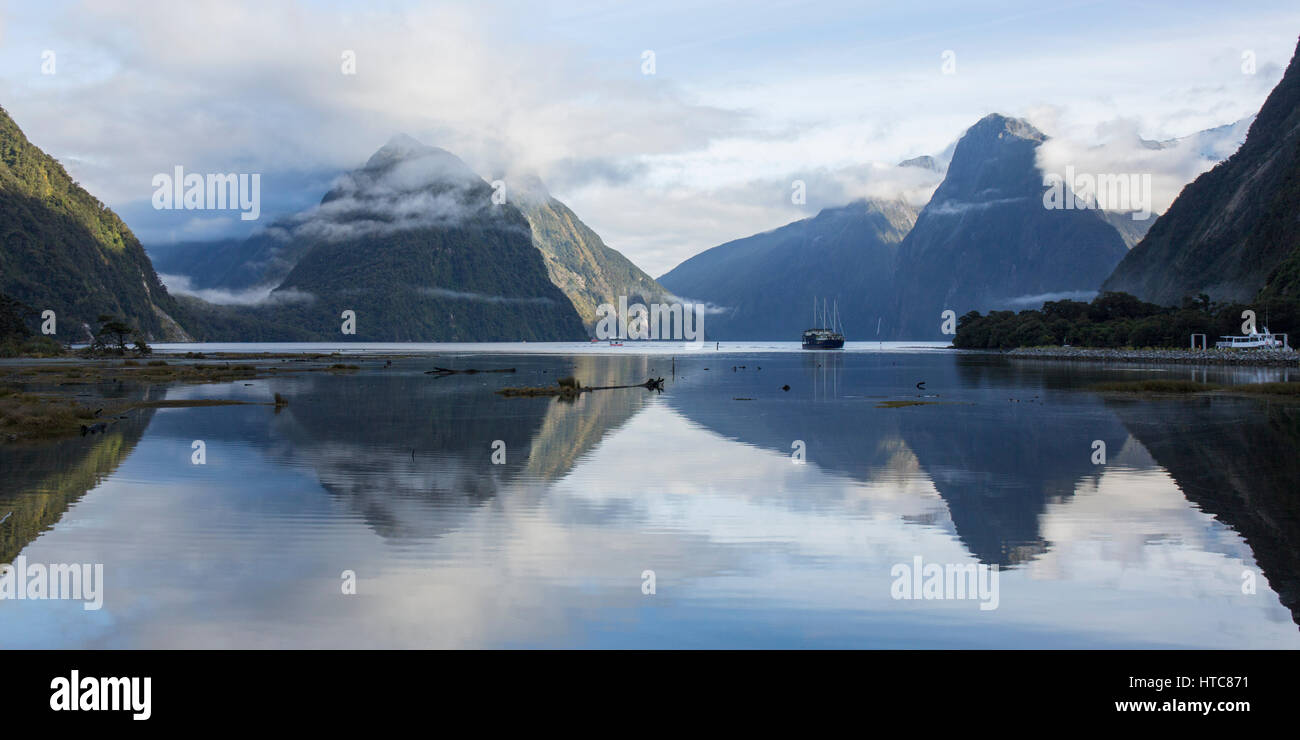Milford Sound, Fiordland-Nationalpark, Southland, Neuseeland. Panoramablick, Milford Sound, Bergspitzen spiegeln sich in stillem Wasser. Stockfoto