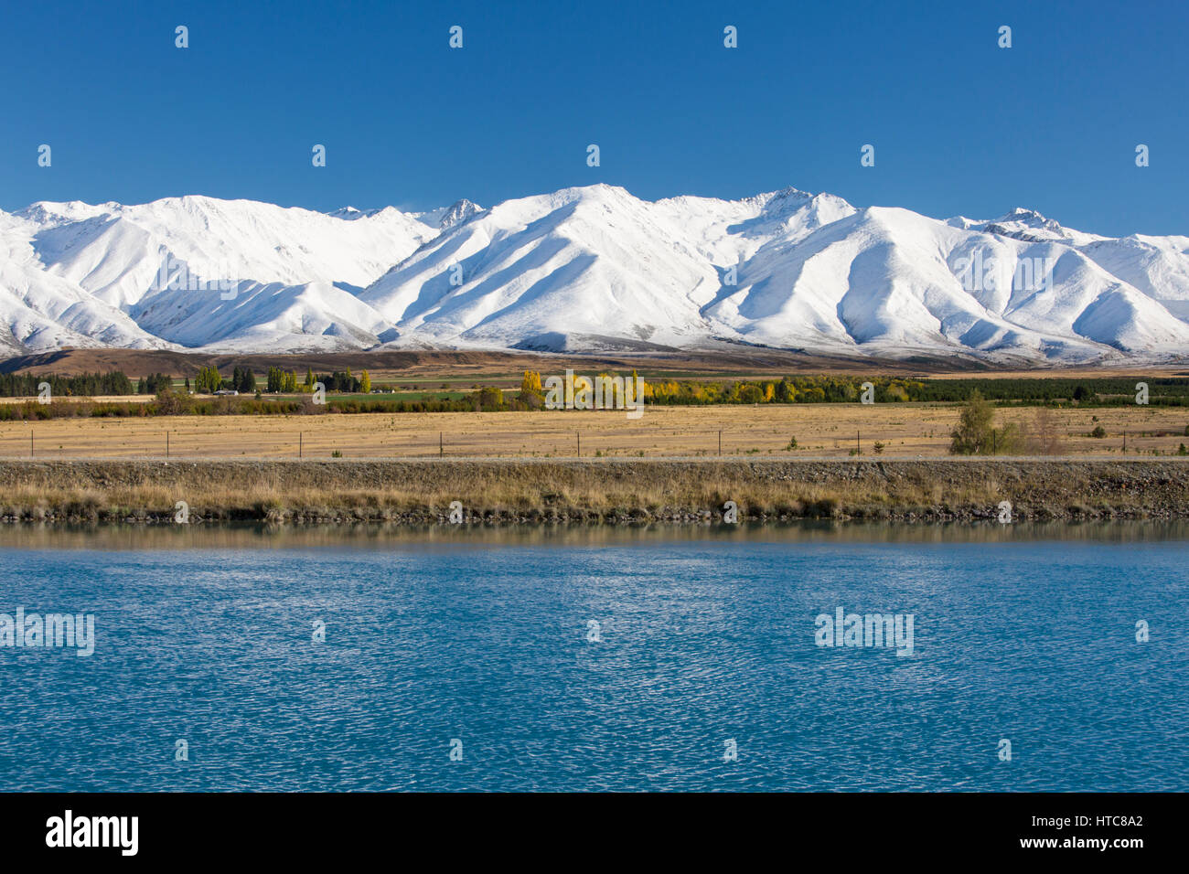 Twizel, Canterbury, Neuseeland. Blick über den Kanal Pukaki zu den schneebedeckten Gipfeln des Bereichs Ben Ohau Herbst. Stockfoto