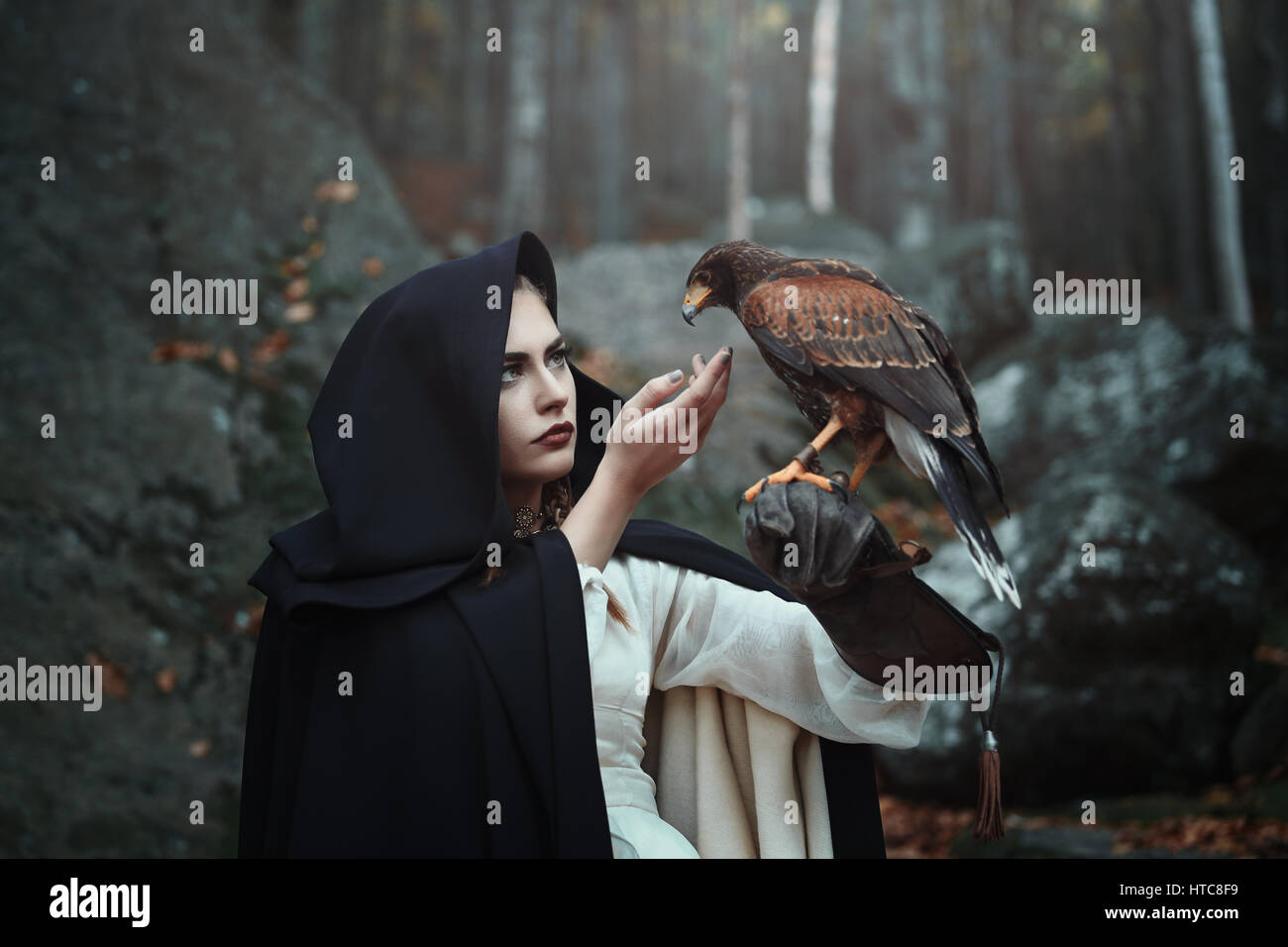 Schwarze Kapuzen Jägerin mit Hawk. Fantasie und Falknerei Stockfoto