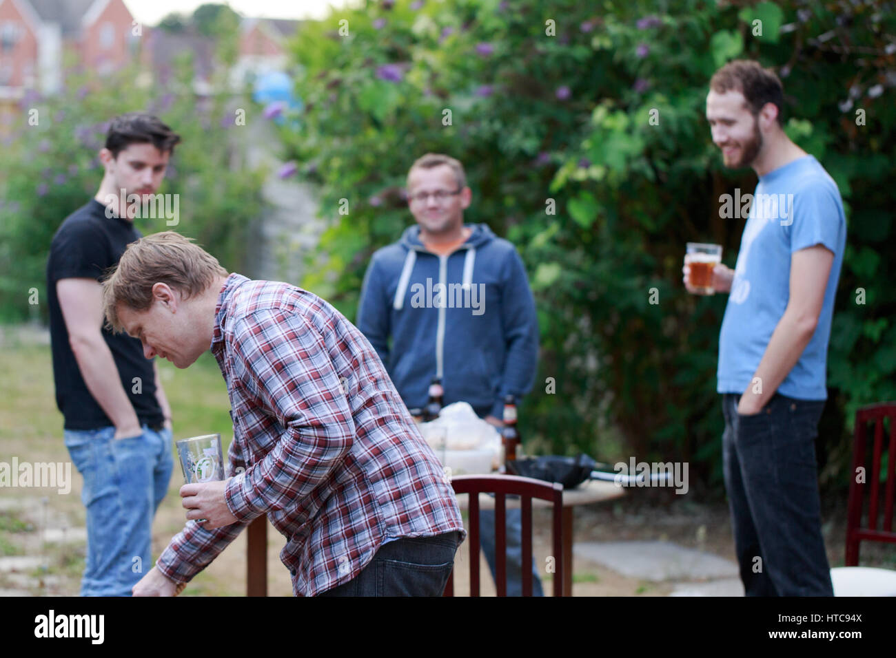 Freundeskreis junger Mann treffen nach der Arbeit zum Biertrinken, Grillen im Garten Garten in Woking, England. Horizontale Komposition Stockfoto