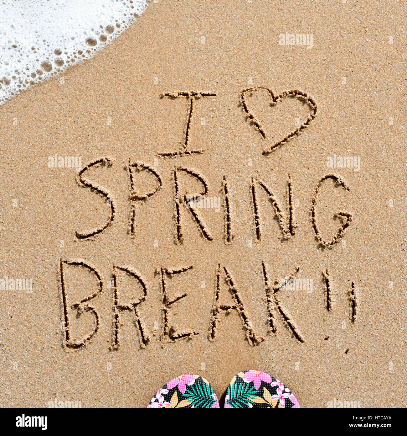Nahaufnahme des Textes ich liebe Frühlingsurlaub in den Sand ein Strand und ein paar bunte Flip-flops geschrieben Stockfoto