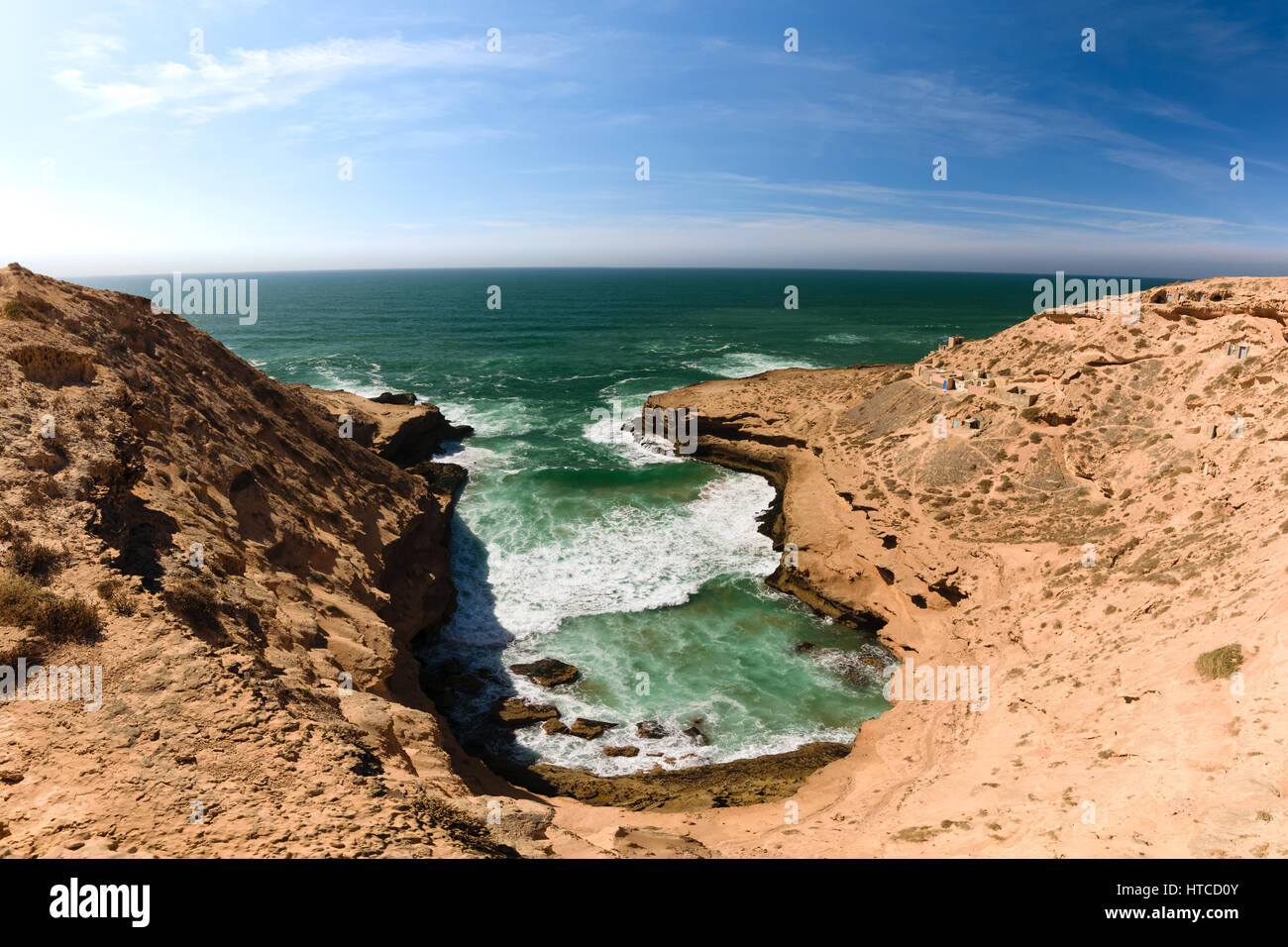 Bunte Küste mit Blick auf eine kleine Bucht mit ein paar Fischen Lodges im Souss-Massa-Nationalpark am Atlantik in Morooco, Afrika. Stockfoto