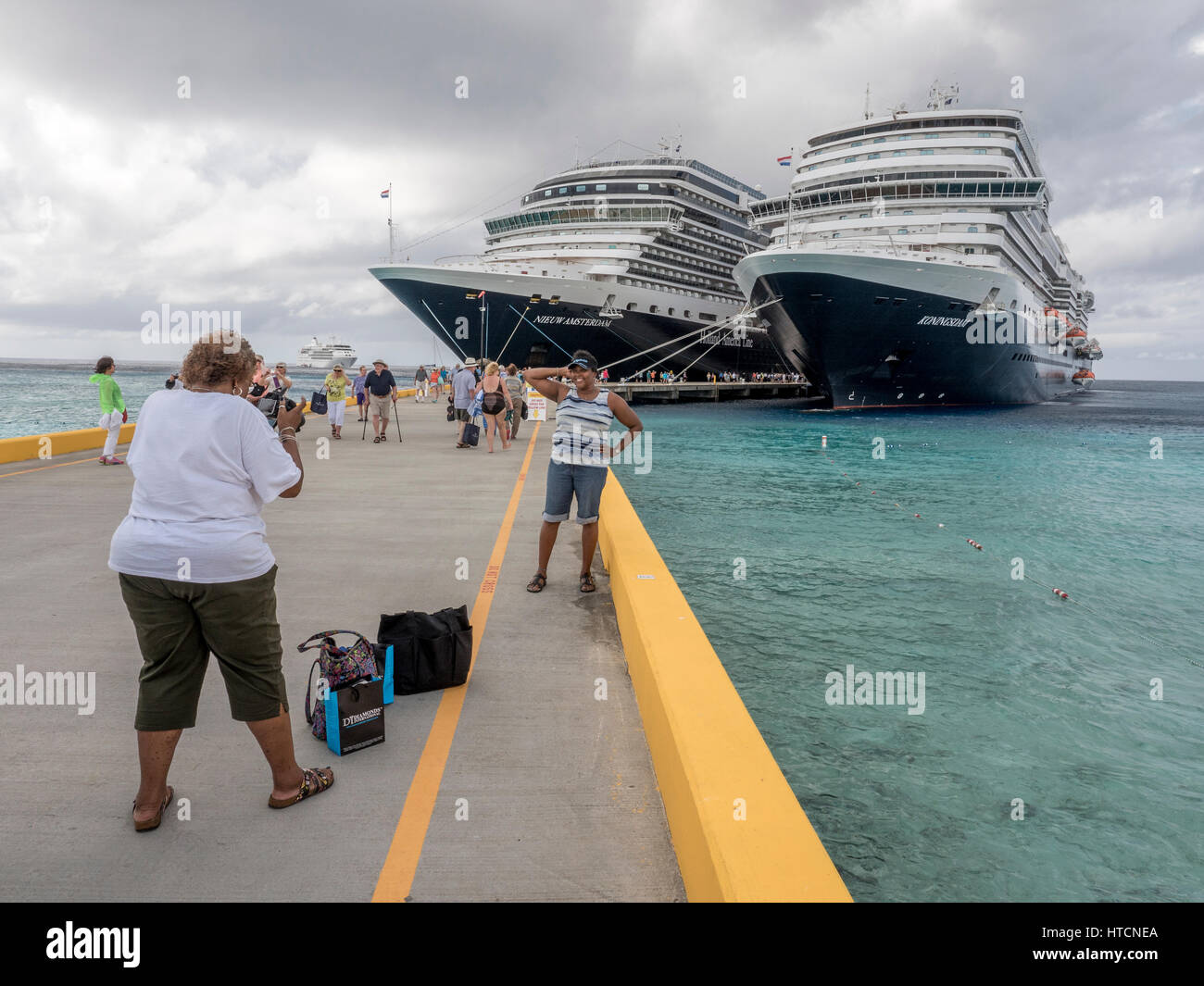 Eine afrikanische amerikanische Frau nimmt ein Foto von ihrer Freundin posiert vor Holland America Kreuzfahrt-Schiffe In Grand Turk Stockfoto