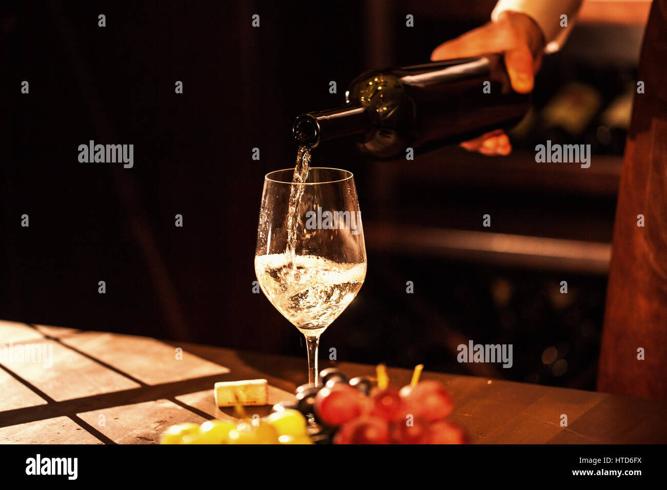 Hand halten Sie eine Flasche Wein und Wein in ein Glas gießen. Weinkeller. Stockfoto