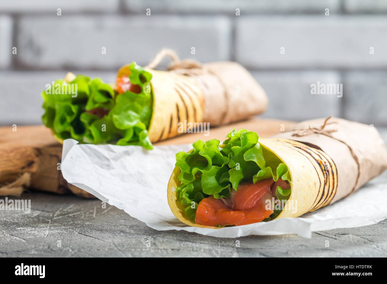 frische Tortilla-Wrap mit Gemüse und Lachs auf Papier Stockfoto