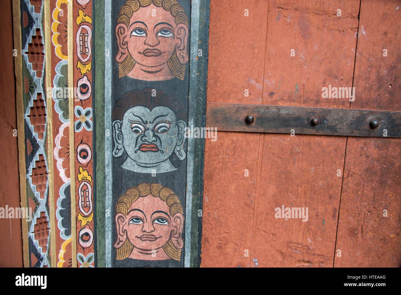 Bhutan Thimphu. Chong Gia ca Tempel. Detail der kunstvoll bemalten Gesichtern um hölzerne Tempeltür. Stockfoto