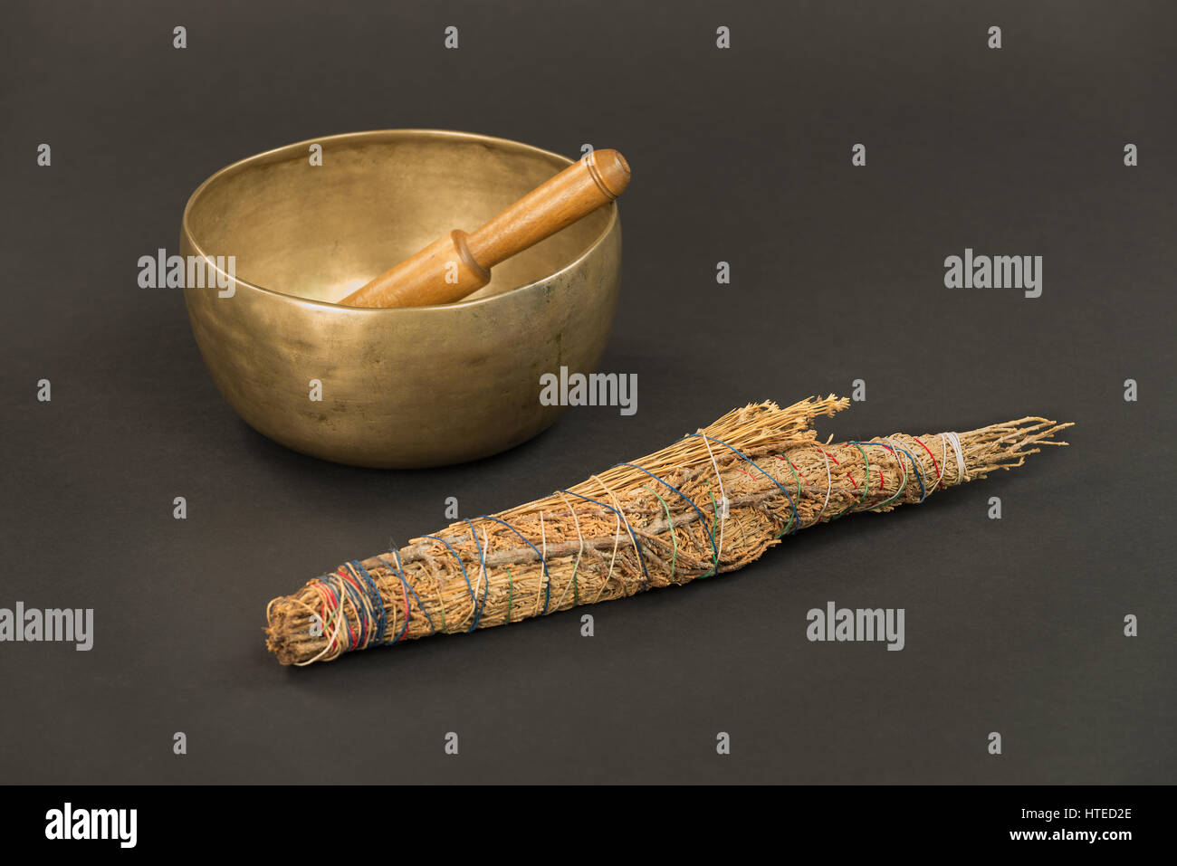 Bronze Tibetische Klangschale mit hölzernen klingeln Stick und große native american smudge Stick auf einem schwarzen Hintergrund. Stockfoto