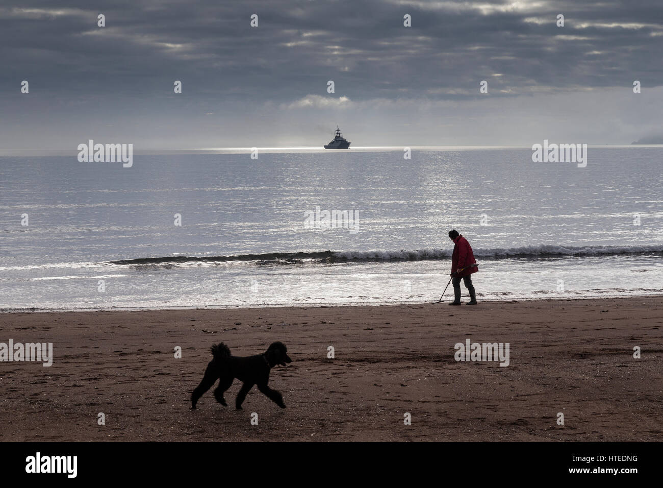 Metall Schatzsucher auf Paignton Beach Schatzsuche, sitzt ein Marineschiff in Torbay mit Berry Kopf im Hintergrund  Stockfoto