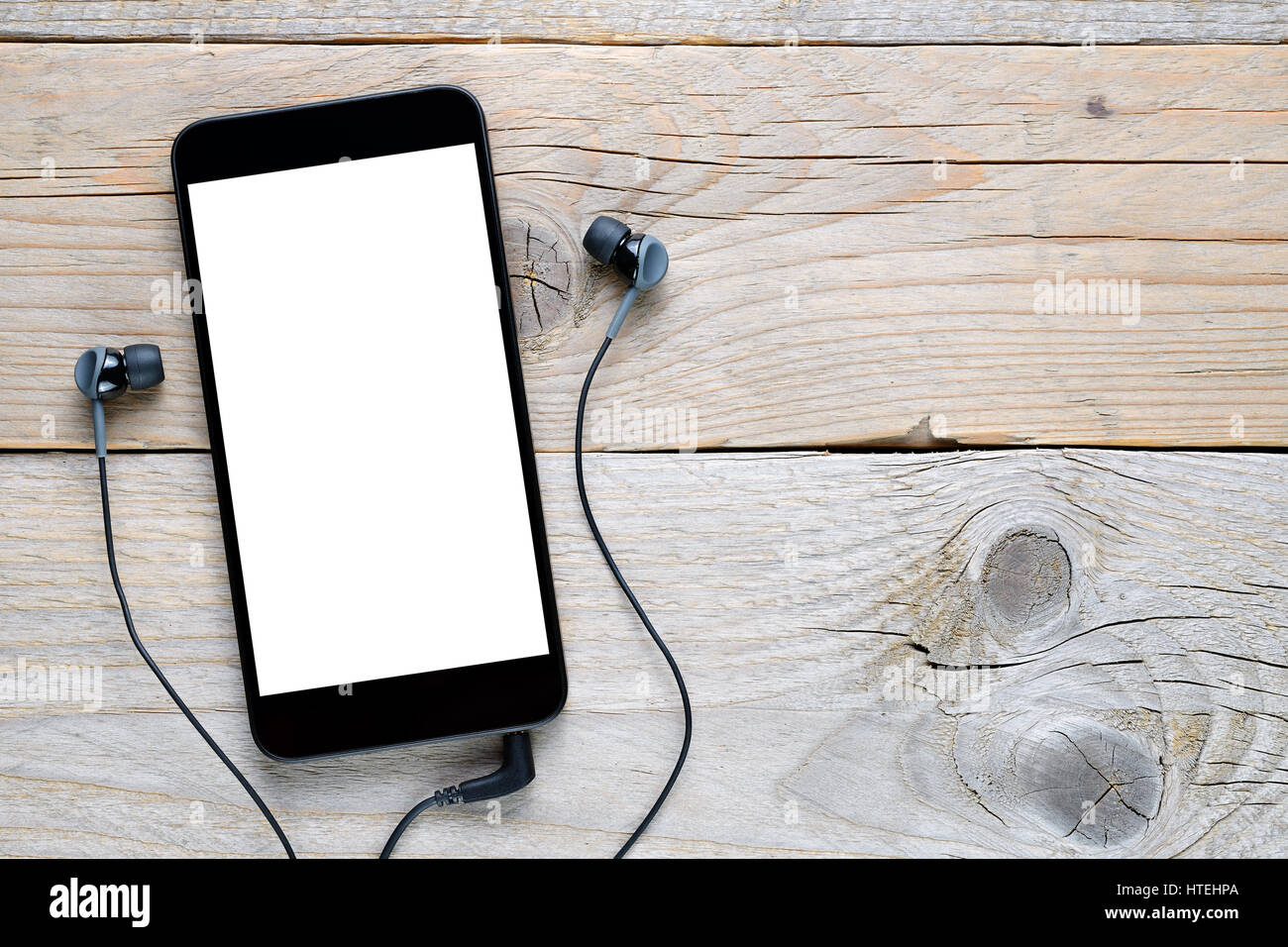 Smartphone mit Kopfhörer auf Holztisch Stockfoto