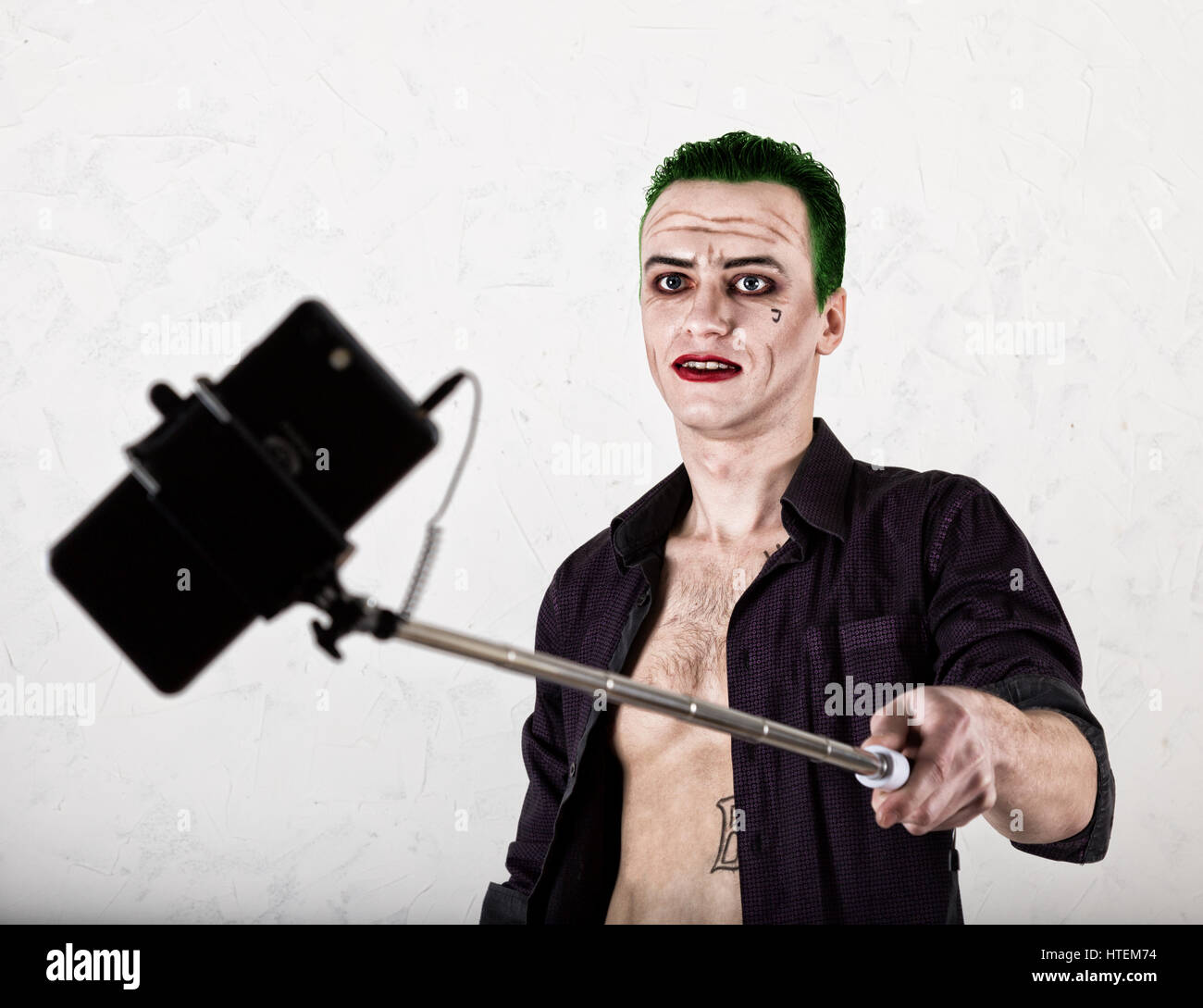 Kerl mit verrückten Joker Gesicht, grüne Haare und idiotische Lächeln. Karneval Kostüm. selfy Foto zu machen. Stockfoto