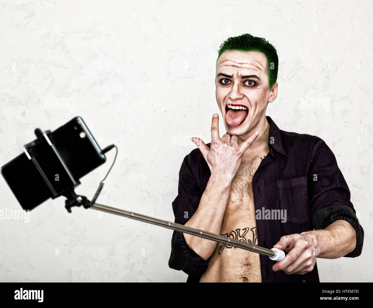 Kerl mit verrückten Joker Gesicht, grüne Haare und idiotische Lächeln. Karneval Kostüm. selfy Foto zu machen. Stockfoto