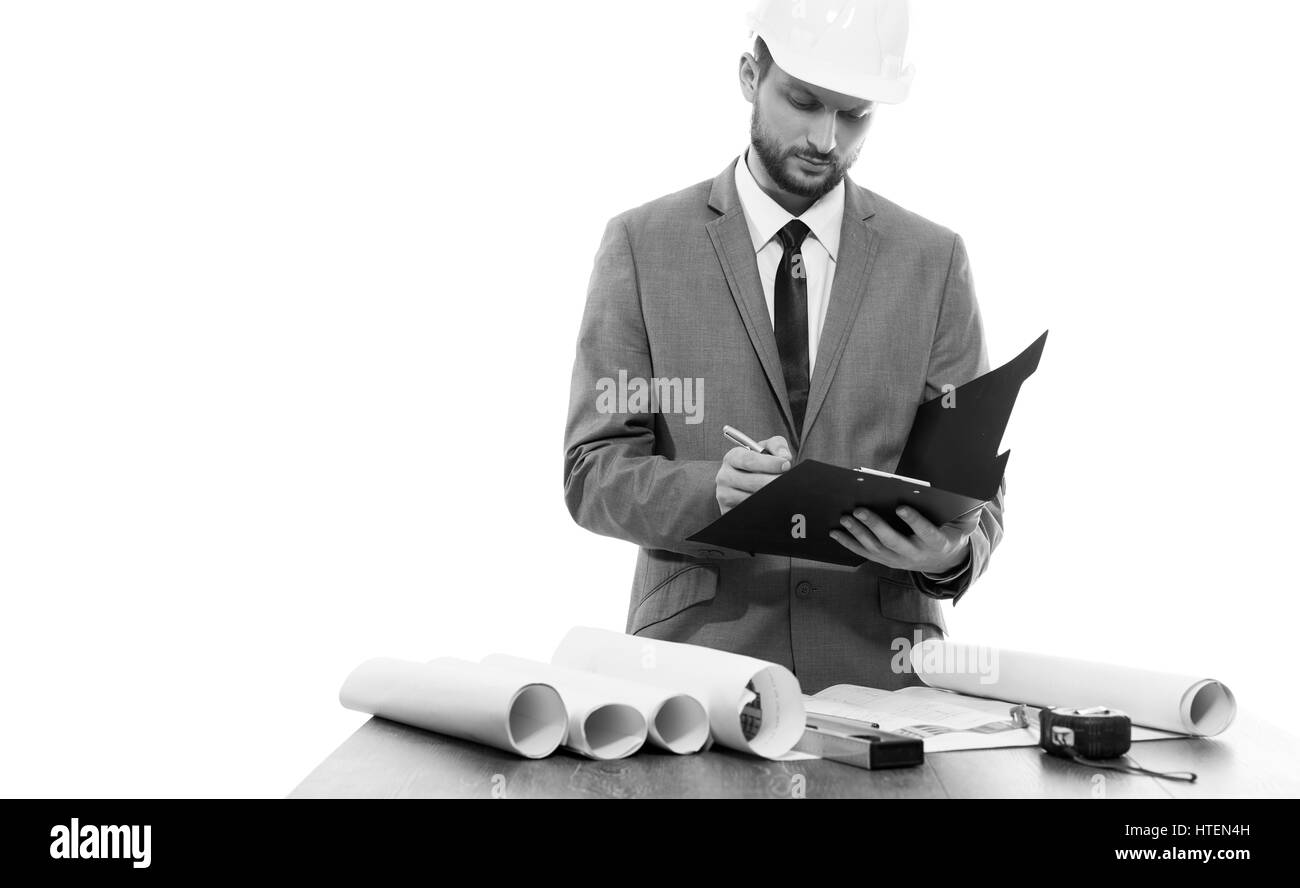 Bau-Profi. Schwarz / weiß Aufnahme eines Geschäftsmann Architekten tragen Schutzhelm schreiben in seine Zwischenablage isoliert Exemplar Dokum Stockfoto