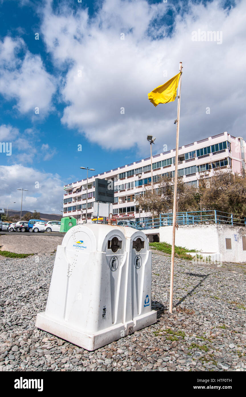 Gelbe Flagge neben einem Container Recycling Glas am Strand, Playa del Águila, Gran Canaria, Kanarische Inseln, Spanien Stockfoto