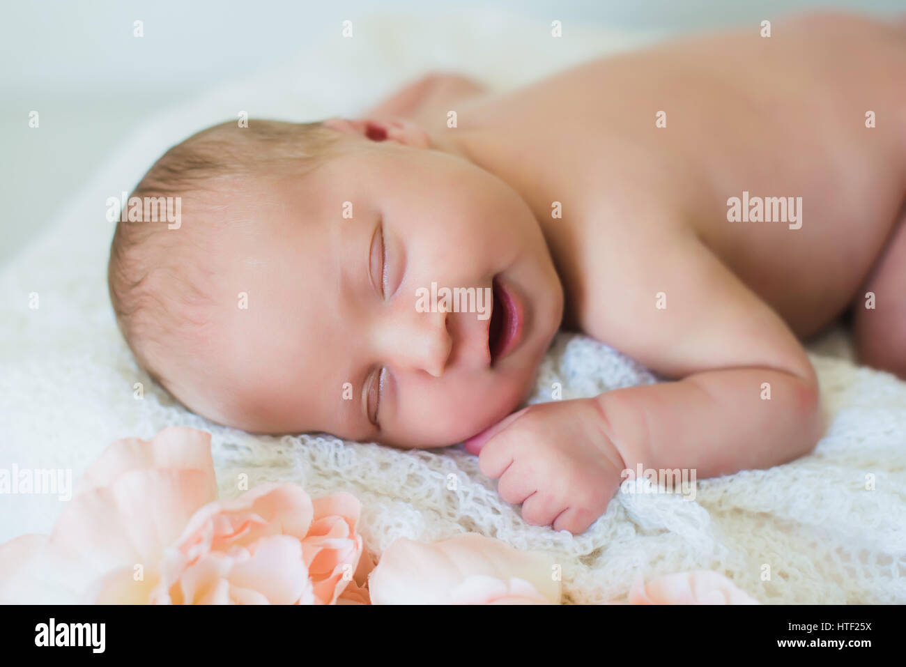 Neugeborenes Baby lächelt. Kopf und Schultern Schuss eines schlafenden zwei Wochen alten Neugeborenen. Hellen Hintergrund, schlafendes neugeborenes Mädchen Stockfoto