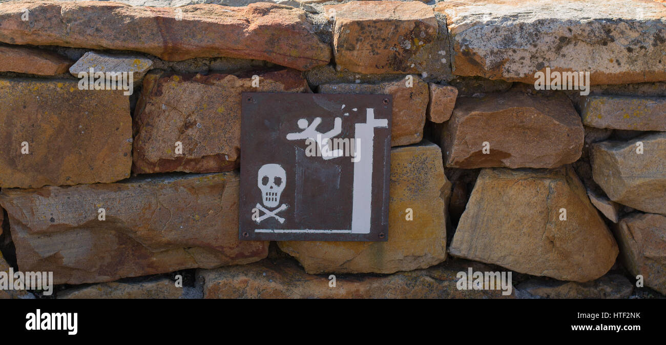 Primitive handgemalte Warnschild mit Totenkopf auf Steinmauer Stockfoto