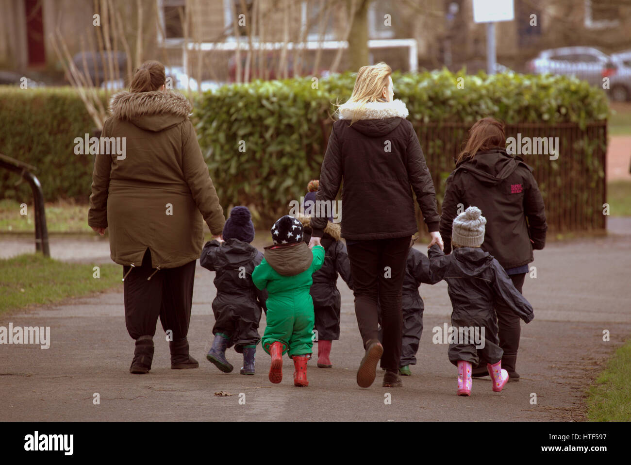 Kleinkinder für Regen zu Fuß mit Erwachsenen im Kelvingrove Park gekleidet Stockfoto