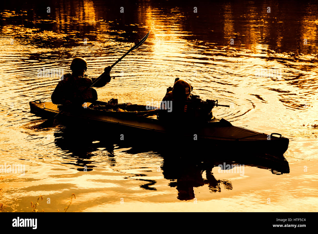 Silhouette von Spezialeinheiten Männer Armee Kajak zu paddeln. Boot über den Fluss, Ablenkungsmanöver Mission, Sonnenuntergang Dämmerung ruhig bewegen Stockfoto