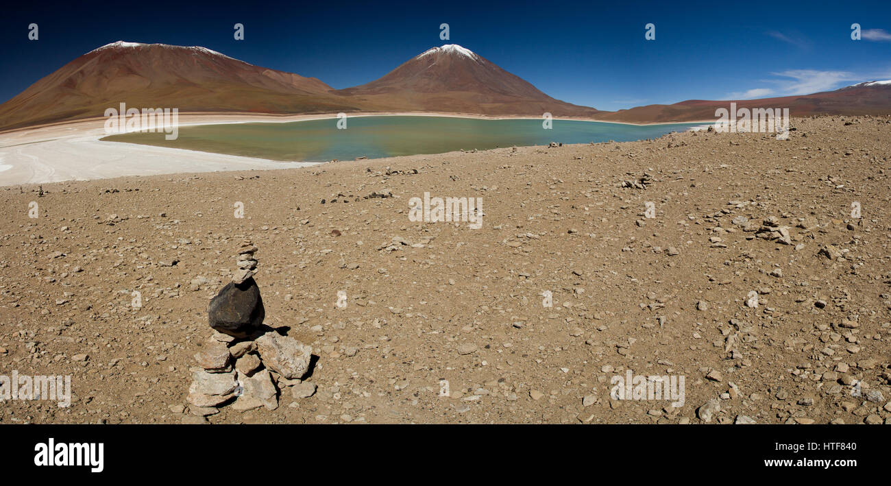 Caldera-See in den Anden, Bolivien mit Schnee bedeckt vulkanische Gipfeln im Hintergrund und Cairn von Steinen im Vordergrund Stockfoto