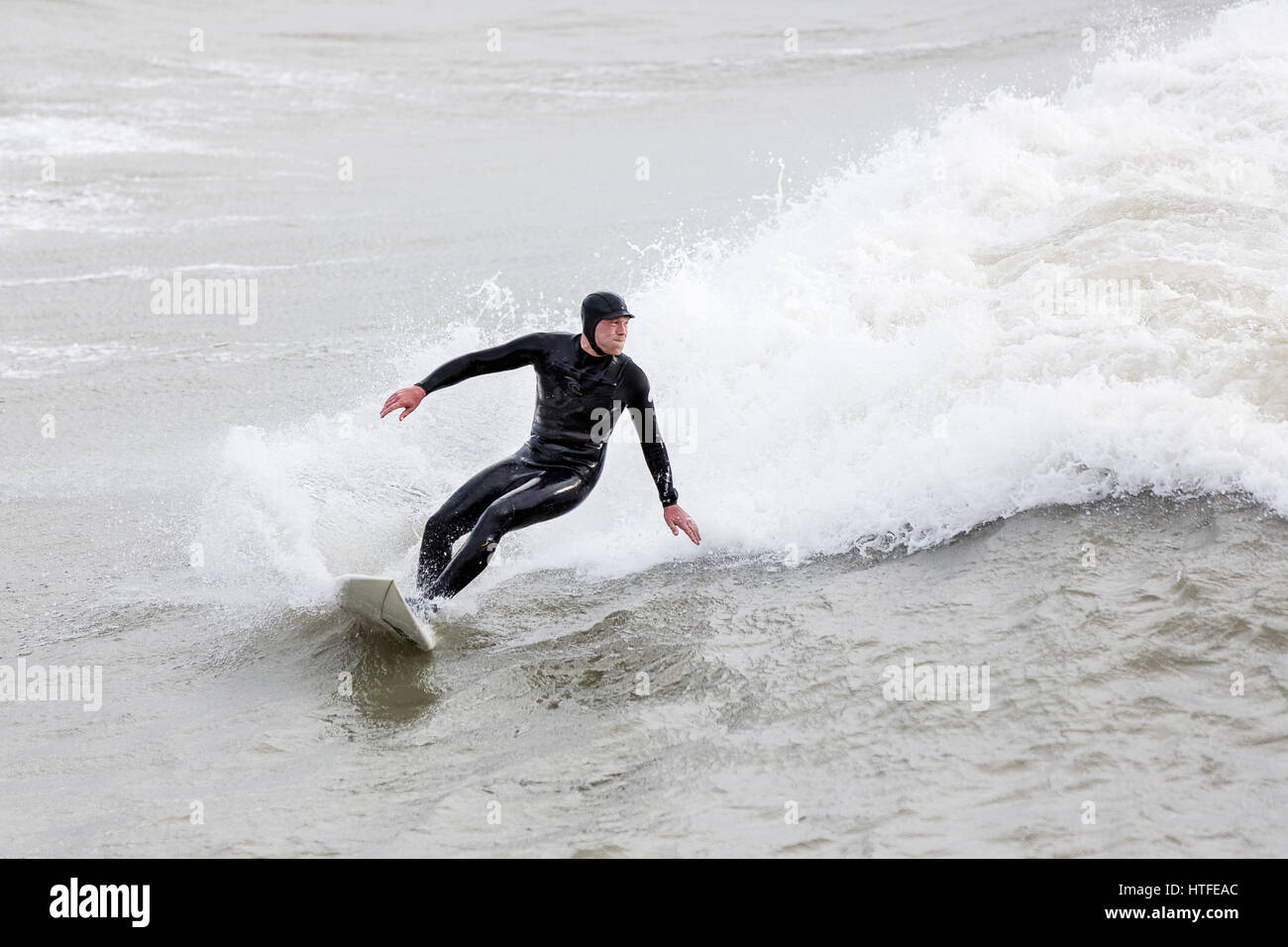 Ein Surfer nutzt die Vorteile von stürmischer See in Bournemouth, Dorset, England und fährt eine große Welle Überschrift in ans Ufer Stockfoto