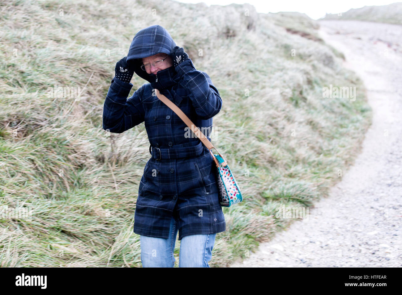 Eine Frau ist gezwungen, ihr Fell Kapuze halten wie Starkregen, angetrieben von starken Winden versuchen die Kapuze vom Kopf zu blasen. Sie wurde von einem Sturm gefangen Stockfoto