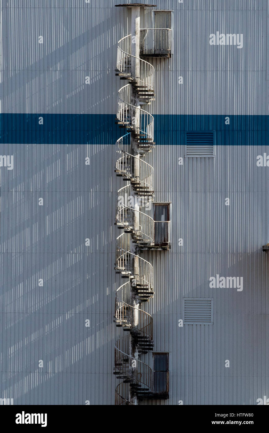 Industrielle Wendeltreppe verbindet drei Ebenen mit langen Schatten von einem sonnigen Tag in Guipuzcoa (Baskenland, Spanien) 2017. Stockfoto