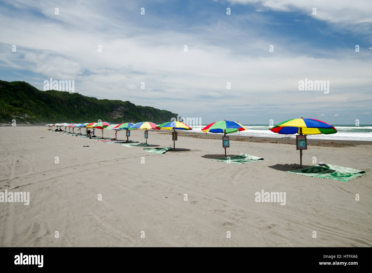 Reihe von bunten Sonnenschirmen am Strand Parangtritis in Zentraljava, Indonesien Stockfoto